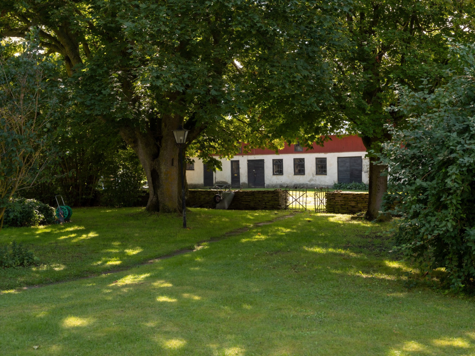 Ett antal vårdträd skuggar gången ut mot storgården och den f d ladugården Havdhem Stora Hajslunds 616