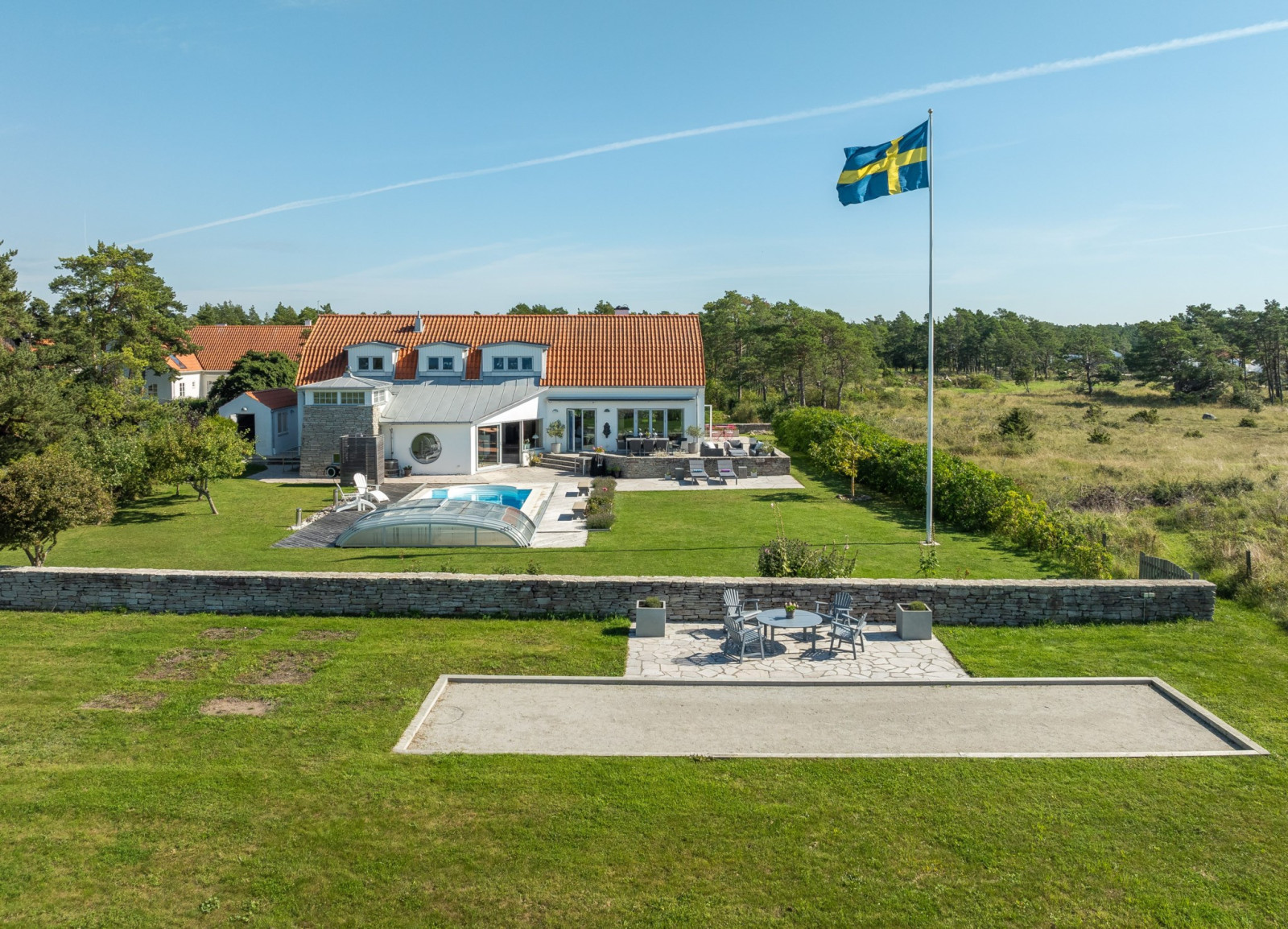 Boulebana med stensatt terrass och flagga i topp. Sanda Havsstigen 12