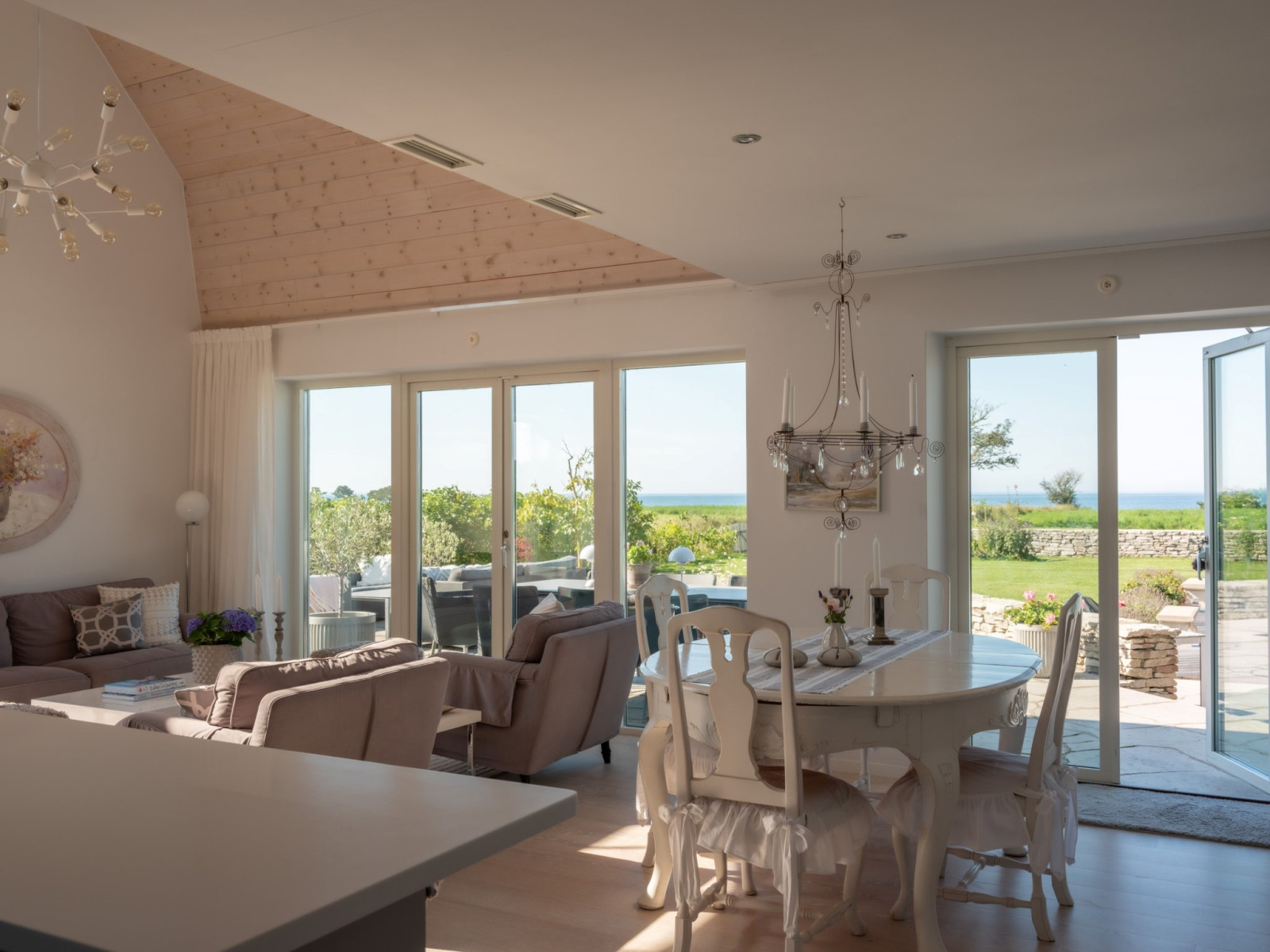 Vardagsrum t v och matsalsbordet t h  och utgång till terrass och poolområde åt väster, åt havet. Sanda Havsstigen 12